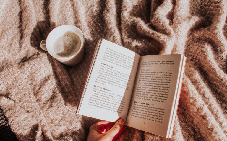 Person reading a book with a beverage on the side